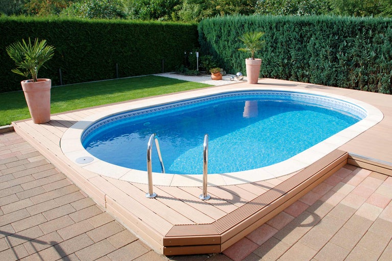 Zwembad met houten terras en trap in een tuin.