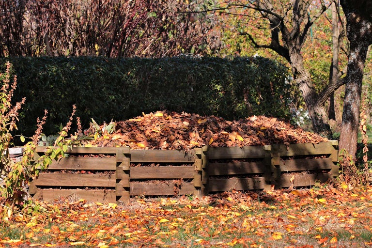 Houten compostbak gevuld met bladeren in de tuin