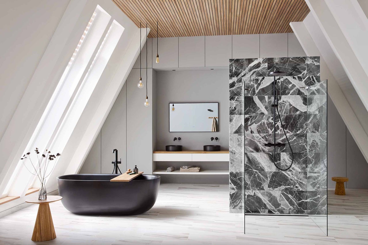 Lichte badkamer met schuine wanden, zwart bad, wastafelmeubel met twee wasbakken, doucheruimte met marmeren tegels en houten elementen