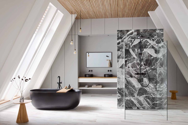 Lichte badkamer met schuine wanden, zwart bad, wastafelmeubel met twee wasbakken, doucheruimte met marmeren tegels en houten elementen