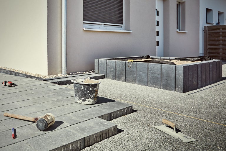 Buitenkant met straatstenen, rubberen hamer, troffel en mortelemmer voor de gevel