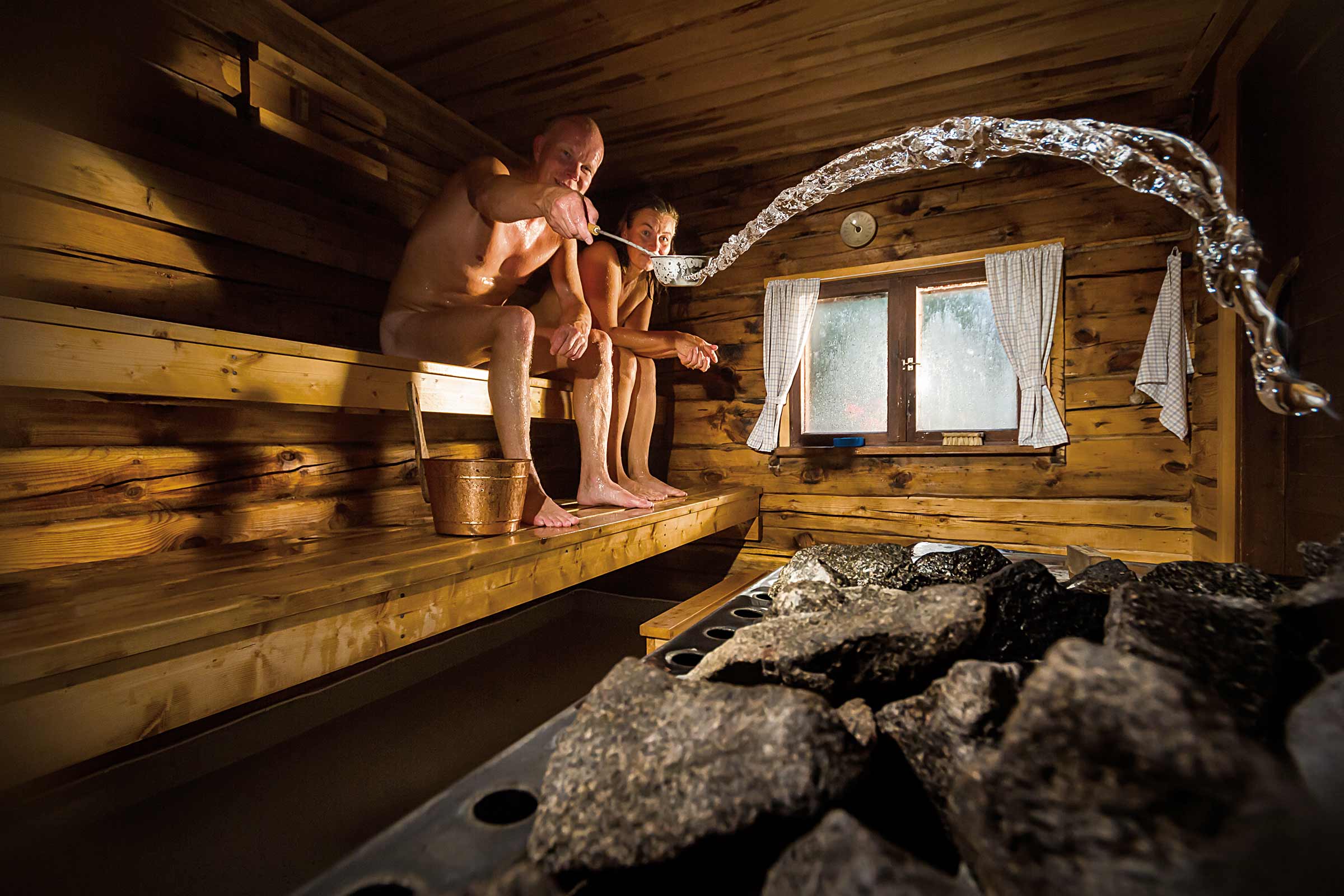 Sauna met mensen, waterlepel, water en stenen