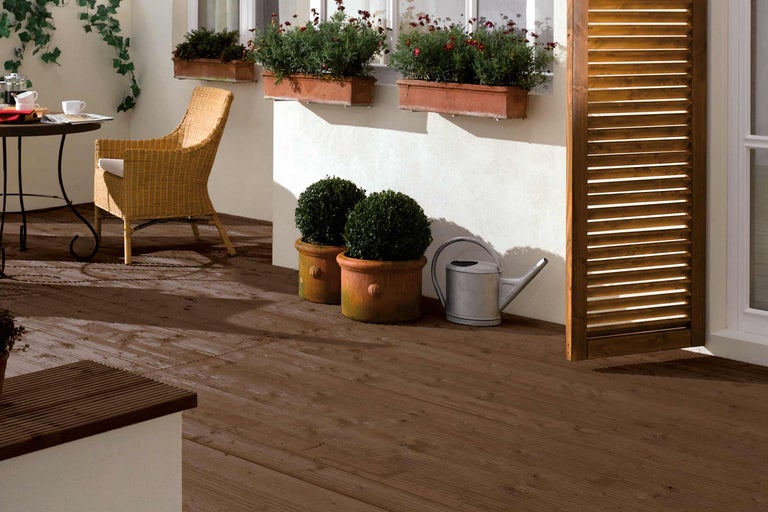 Terras met houten tegels, tafel, stoel, planten en gieter