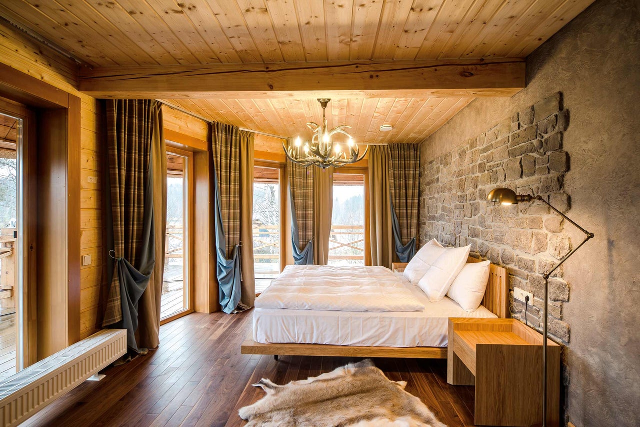 Slaapkamer met houten balkenplafond, stenen muur en bed