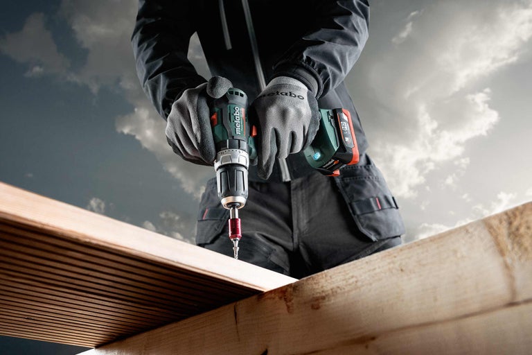Persoon boort met Metabo accuslagboorschroevendraaier in een houten plank.