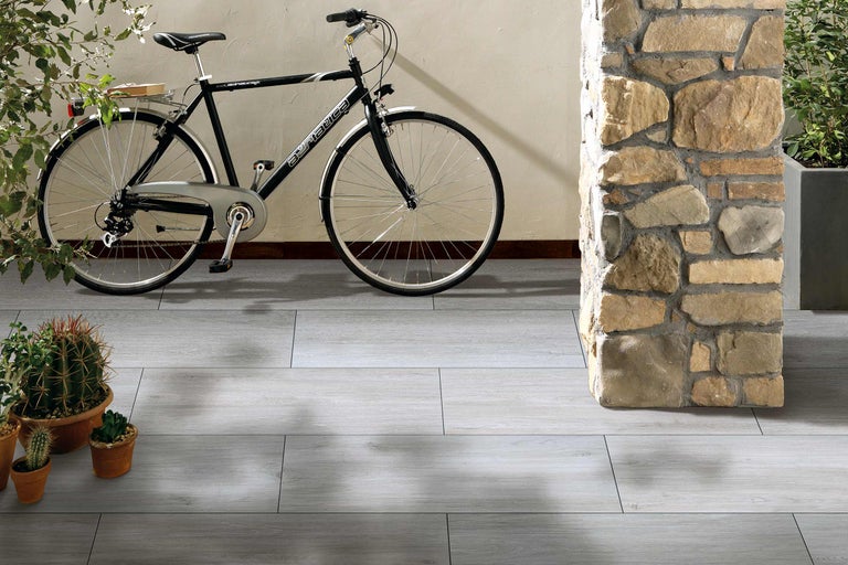 Vloer met grijze tegellook, fiets en stenen zuil