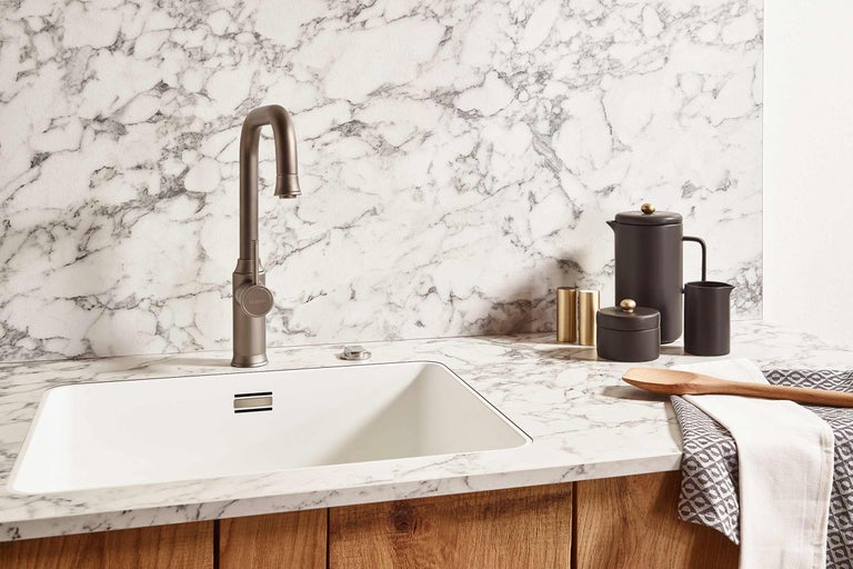 Keukenspoelbak met kraan en keukengerei op een marmeren aanrechtblad