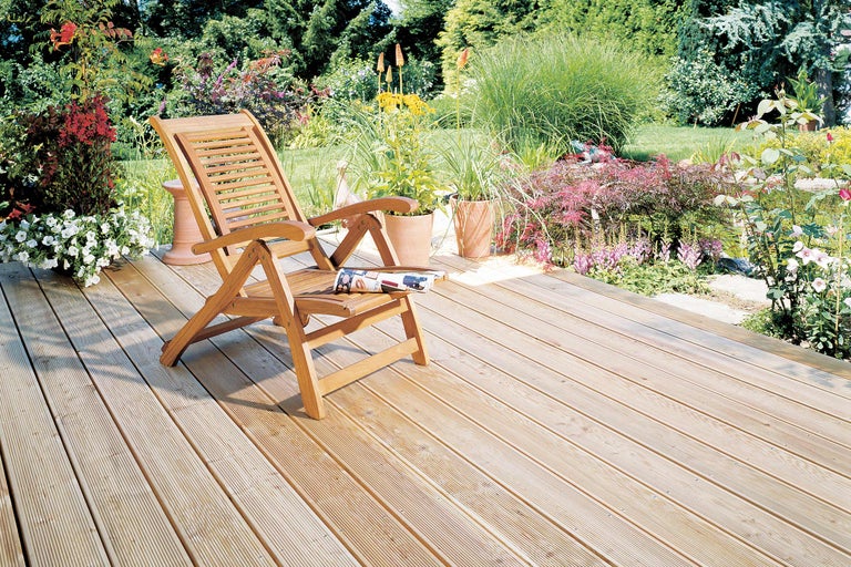 Houten terras met tuinstoel en bloemperken in de tuin