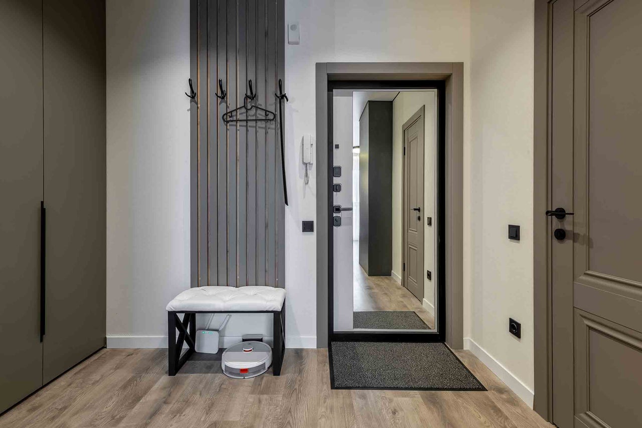 Entree met kapstok, bank, spiegel en robotstofzuiger.