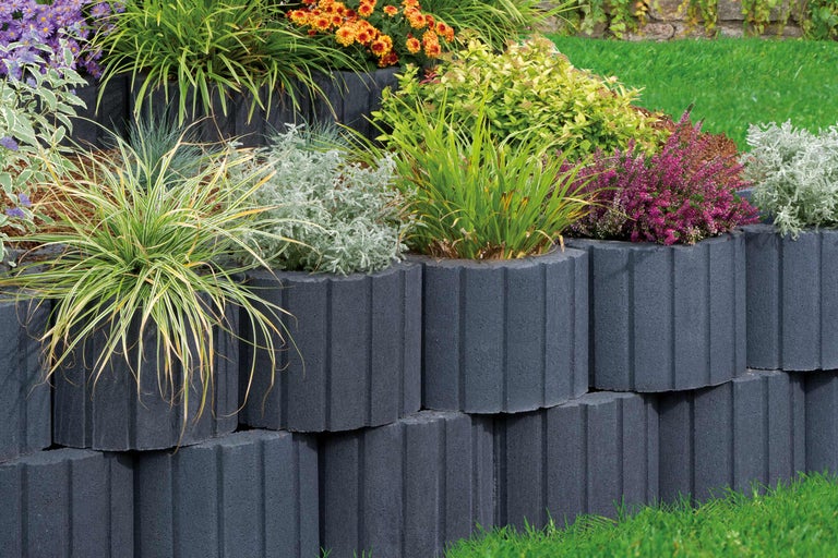 Gestapelde betonnen plantenbakstenen met beplanting in de tuin.