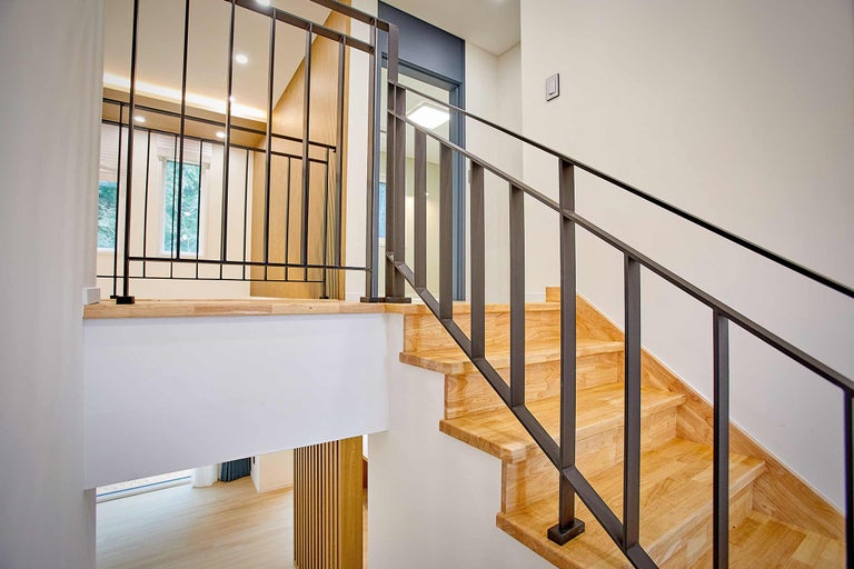 Houten trap met metalen leuning in een licht huis.