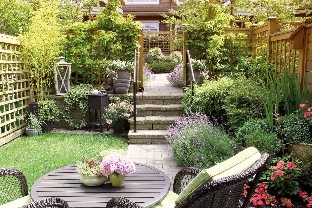 Aangelegde tuin met tafel, stoelen, planten en een betegeld pad