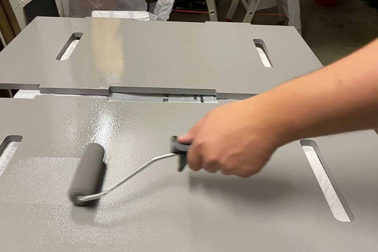 Persoon schildert houten panelen met een verfroller