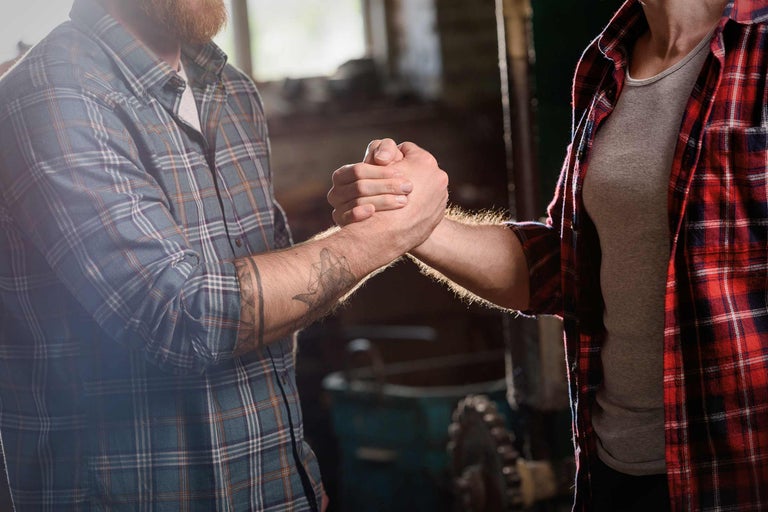 Twee ambachtslieden schudden elkaar de hand als gebaar van samenwerking