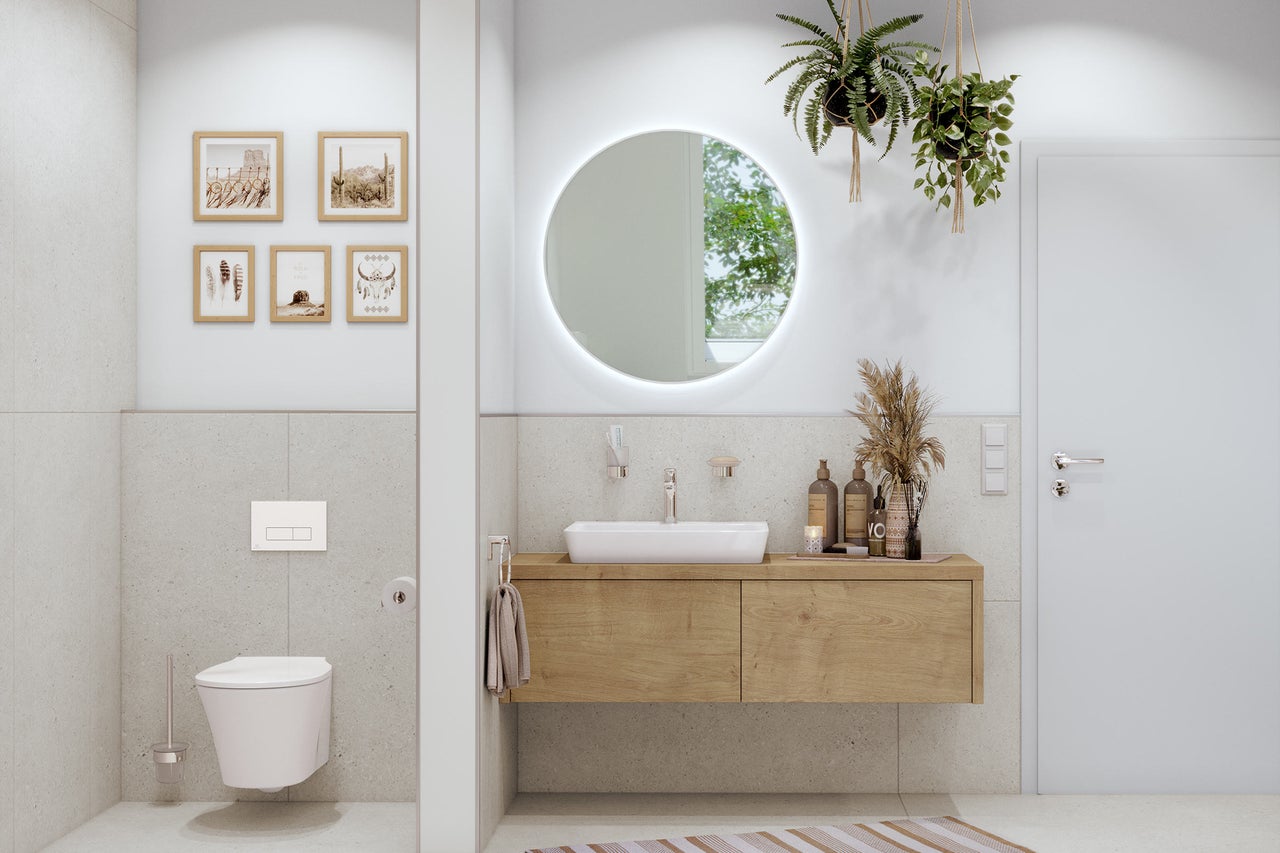 Lichte badkamer met wastafelonderkast, toilet en ronde spiegel