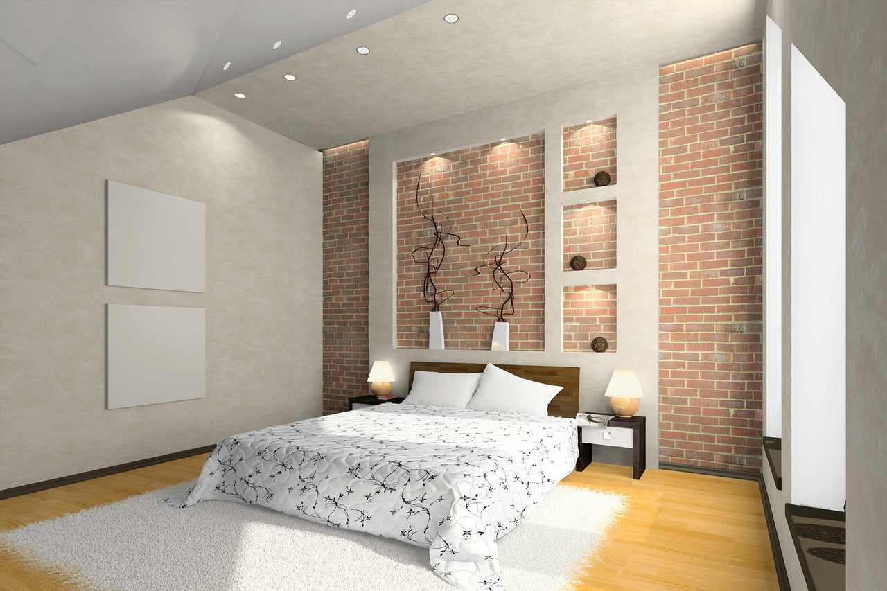 Slaapkamer met tweepersoonsbed, nachtkastjes en bakstenen muur