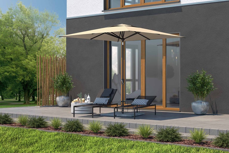 Terras met parasol, ligstoelen en bijzettafel voor een huis