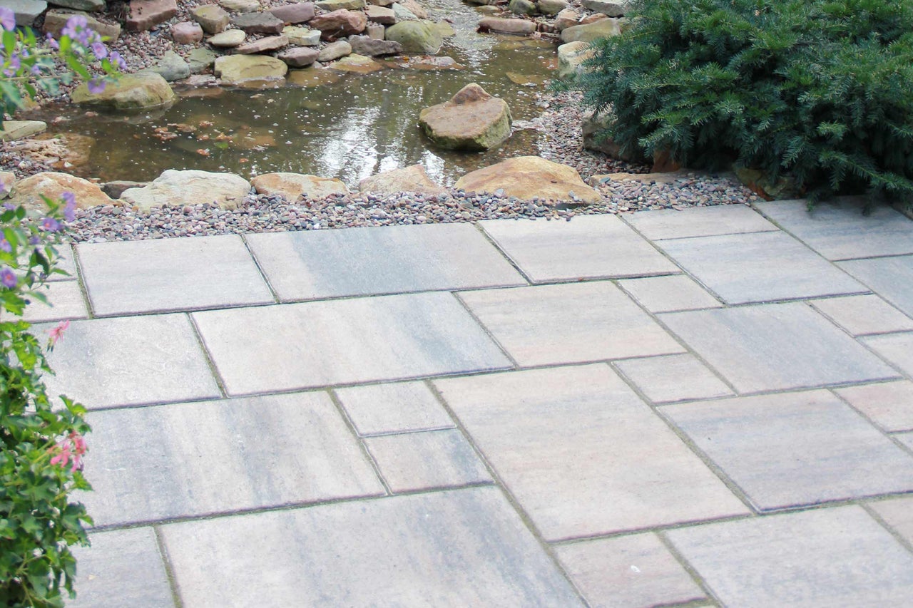 Tuinlandschap met vijver en gelegde bestrating