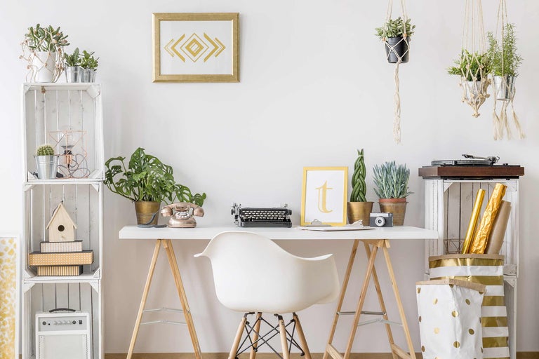 Decoratieve werkplek met bureau, stoel, planten, typemachine en rekken