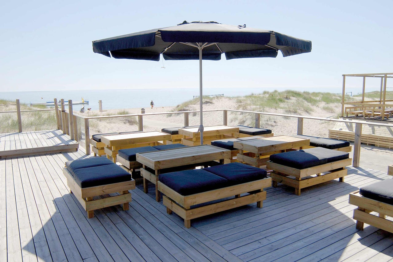Buitengebied met houten vloer, parasol en zitgroepen met kussens