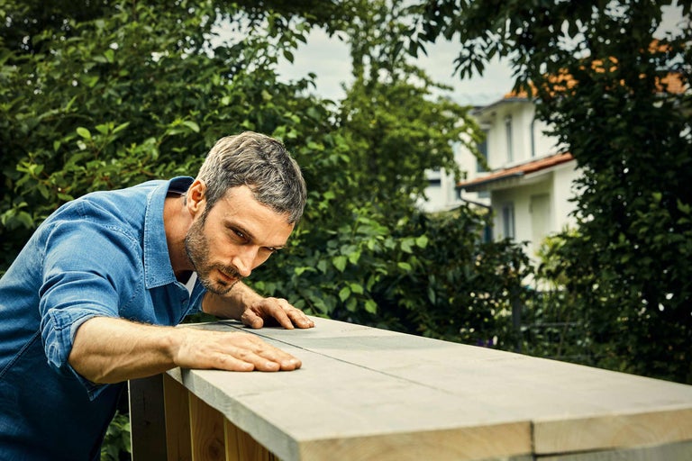 Man inspecteert houten constructie in de tuin