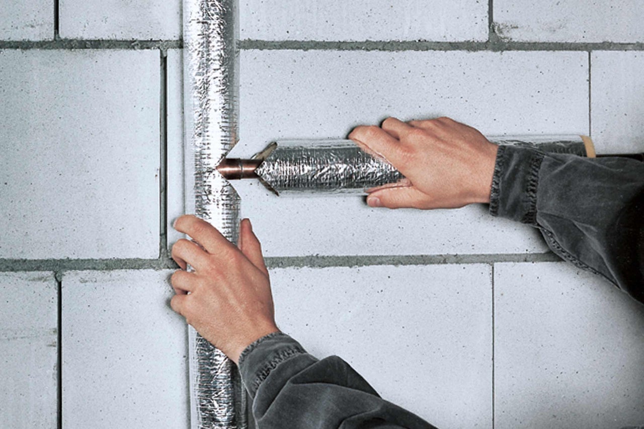 Installatie van een geïsoleerde ventilatieleiding op een muur
