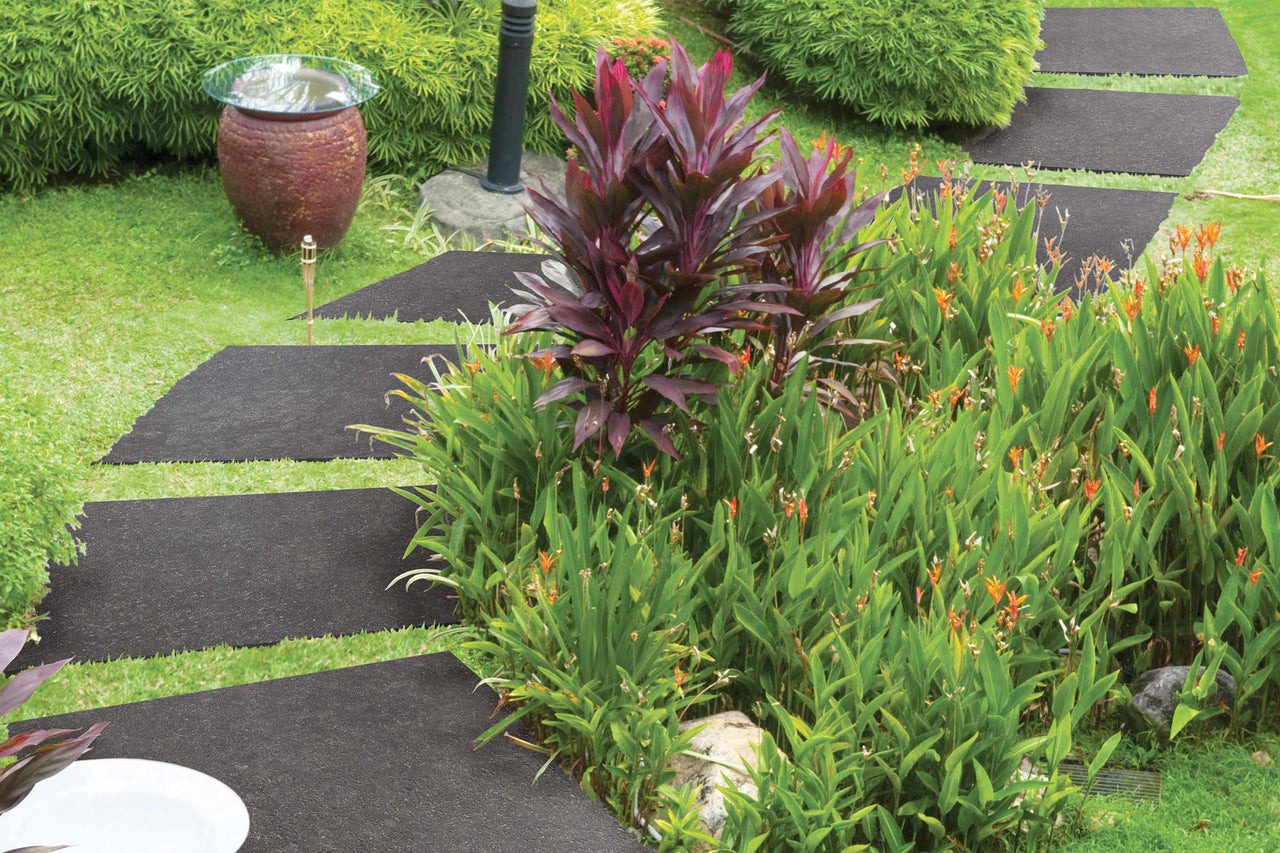 Tuinpad van vloerplaten tussen groene planten