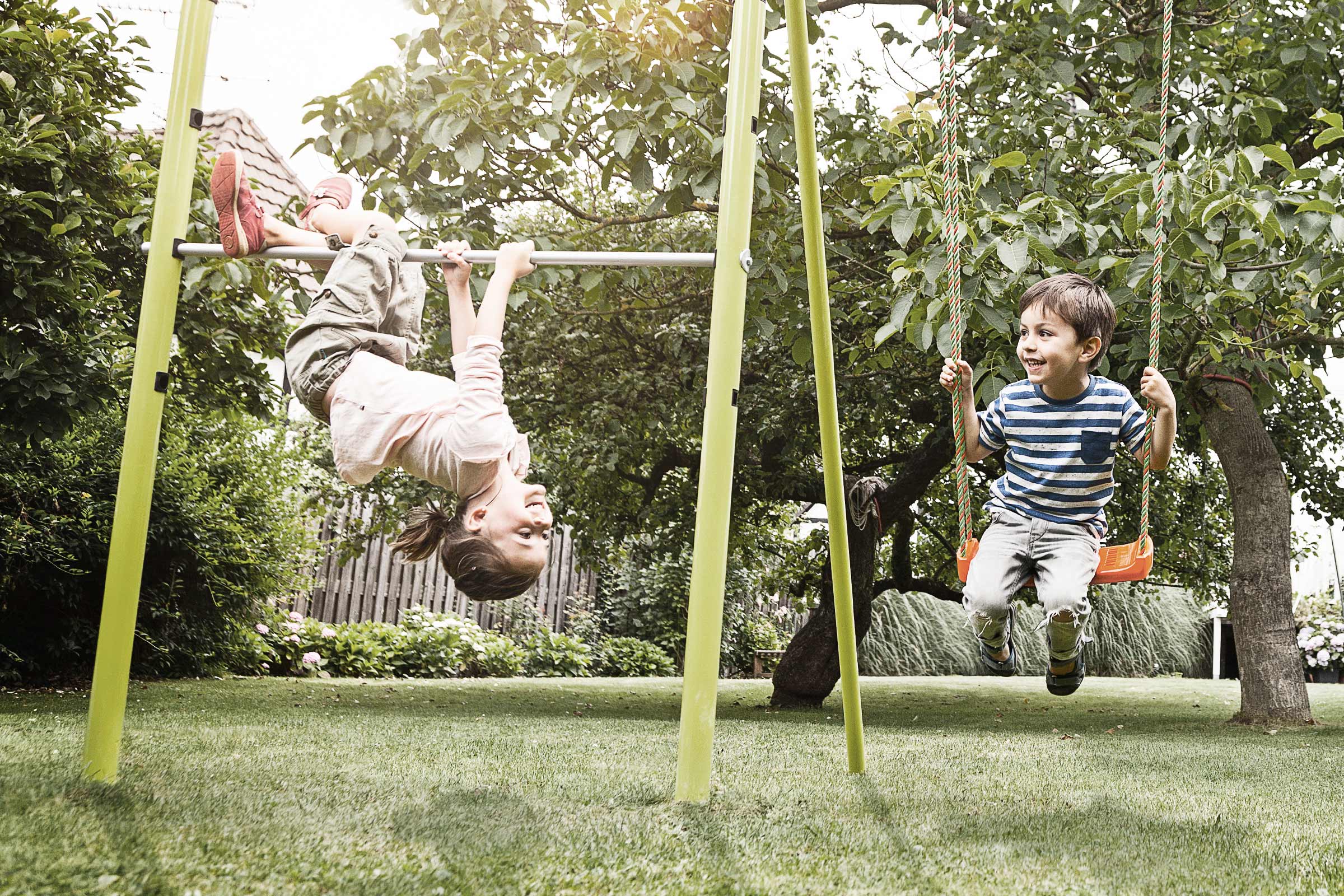 Kinderen spelen in een speeltuin met schommel en rekstok