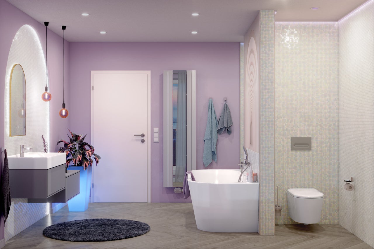 Moderne badkamer met lavendelkleurige muren, vrijstaand bad, hangend toilet, grijs wastafelmeubel en vloer met houtlook.