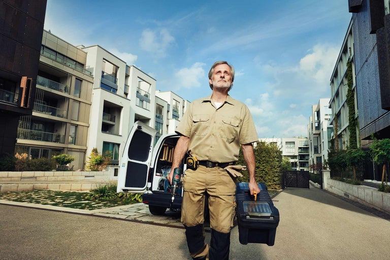 Klusjesman met gereedschapskist en accuschroevendraaier voor zijn bestelwagen