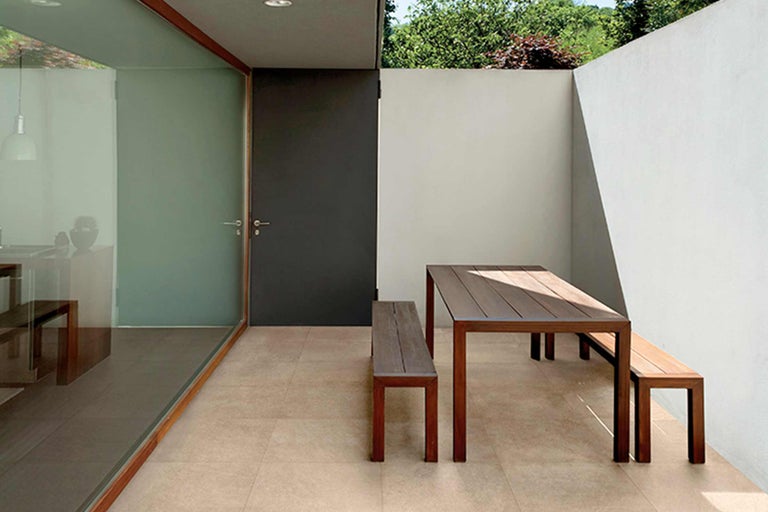 Buitenruimte met houten tafel en houten banken op tegelvloer