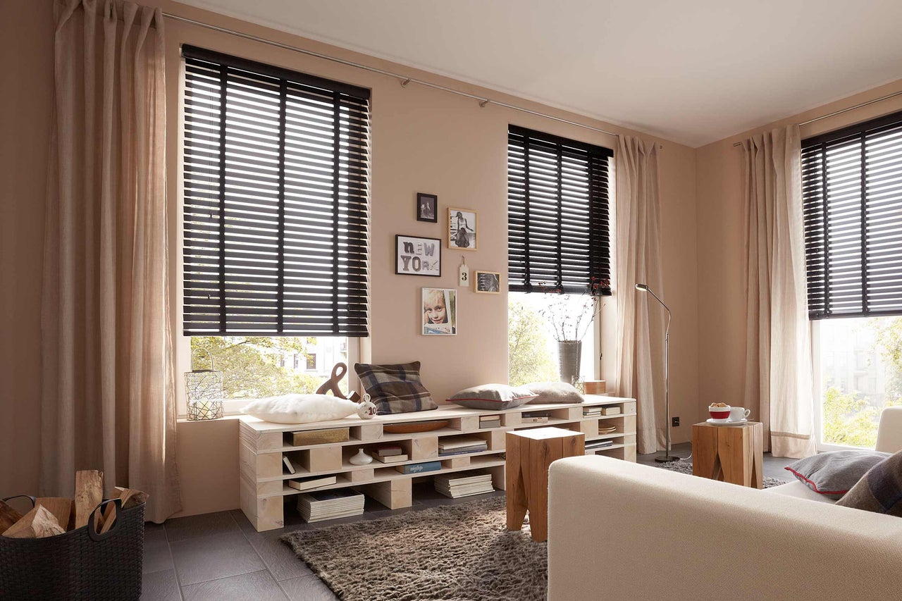 Woonkamer met raam, houten jaloezieën en gordijnen voor privacy en decoratie