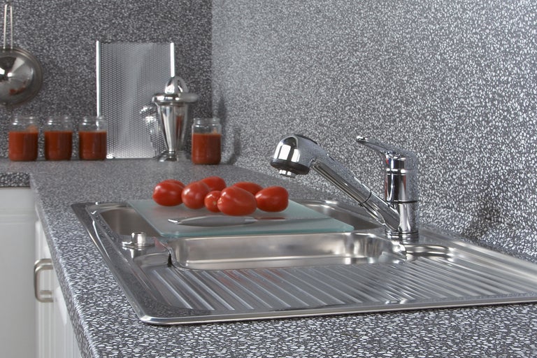 Keukenscène met gootsteen, kraan, snijplank en tomaten op een aanrecht