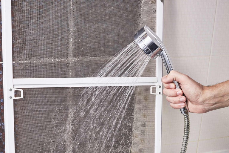 Reiniging van een vliegengaas met een handdouche