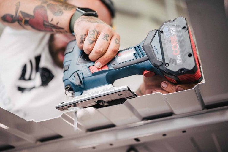 Accu decoupeerzaag in gebruik bij het zagen van een werkstuk.