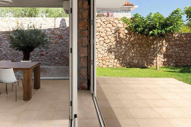 Buitenkant met stenen muur, boom en vloertegels.