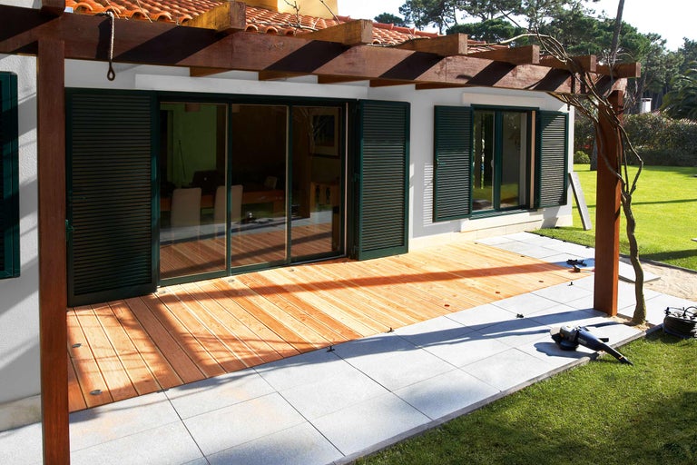 Huis met houten terras en stenen platen in de tuin