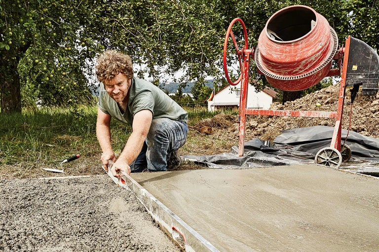 Man maakt beton glad met een rei naast een betonmolen