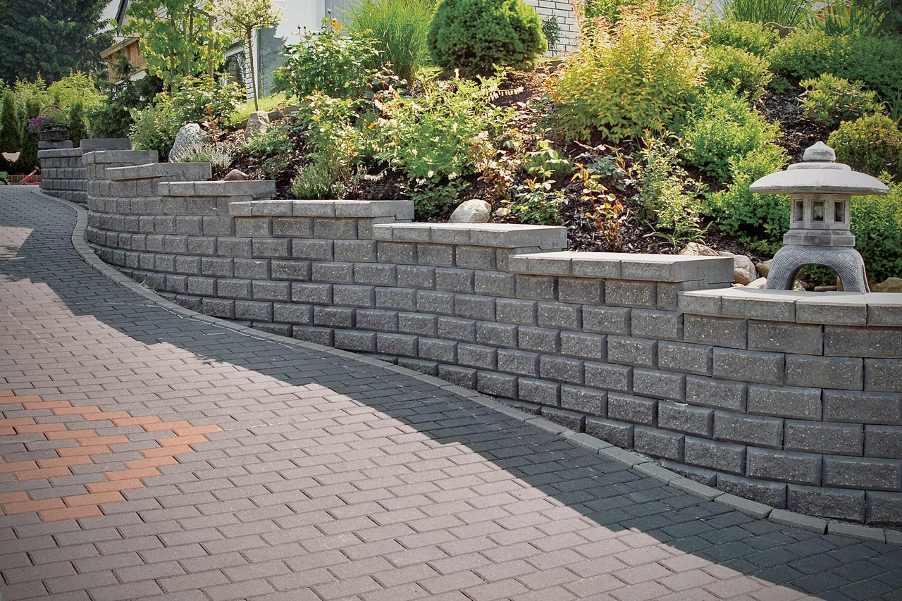 Ontwerpidee voor een tuin met steunmuur en bestrating.