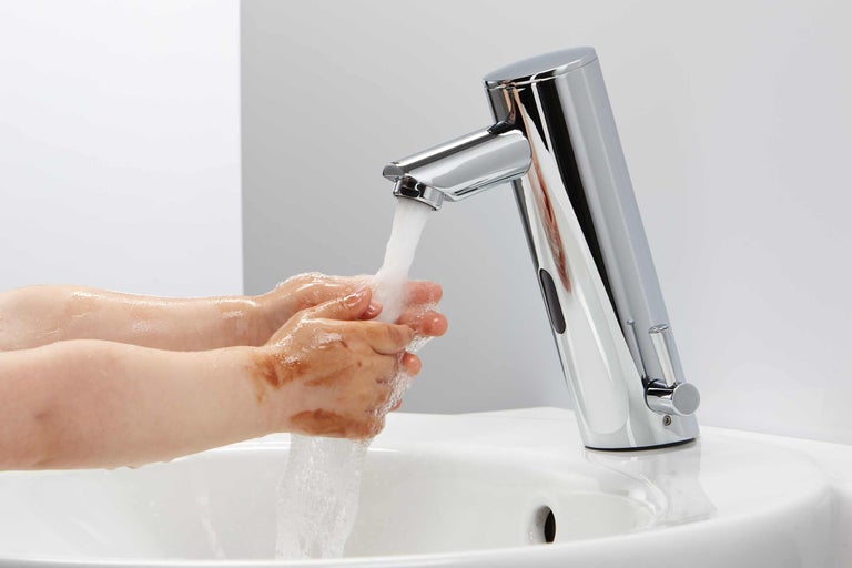 Wastafelkraan met sensor en handen onder stromend water
