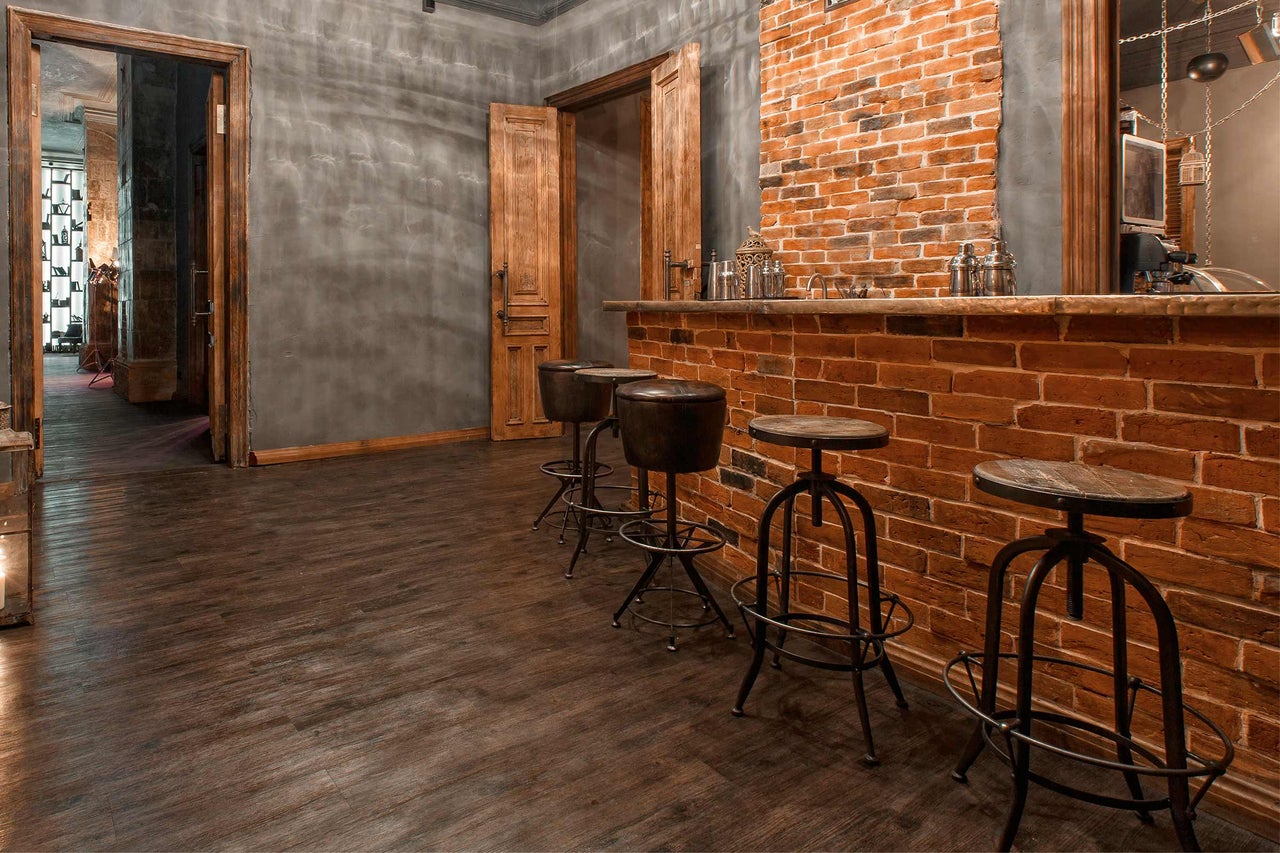 Bar met bakstenen toonbank en barkrukken in een ruimte met houten vloer