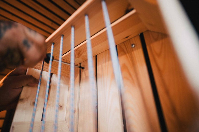 Close-up van een persoon die een houten rek monteert met een schroevendraaier.