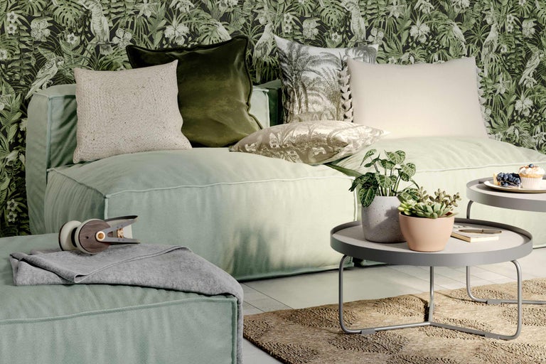 Woonkamer met bank, kussens, bijzettafel en kamerplanten voor een gedessineerd behang