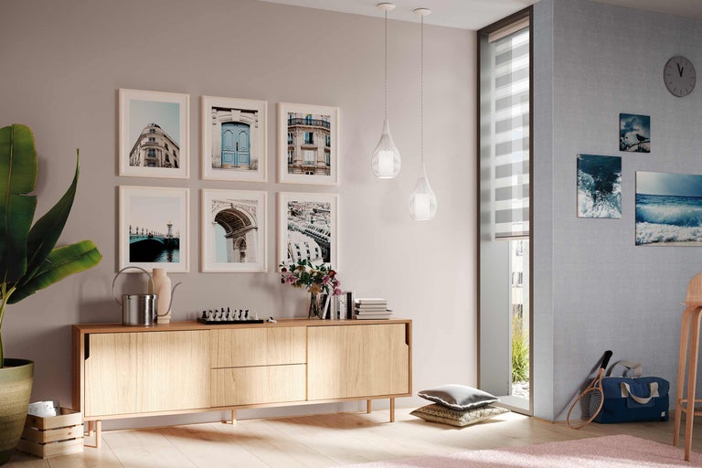 Woonkamer met houten dressoir, schilderijen, hanglampen en decoraties voor een gezellige sfeer.