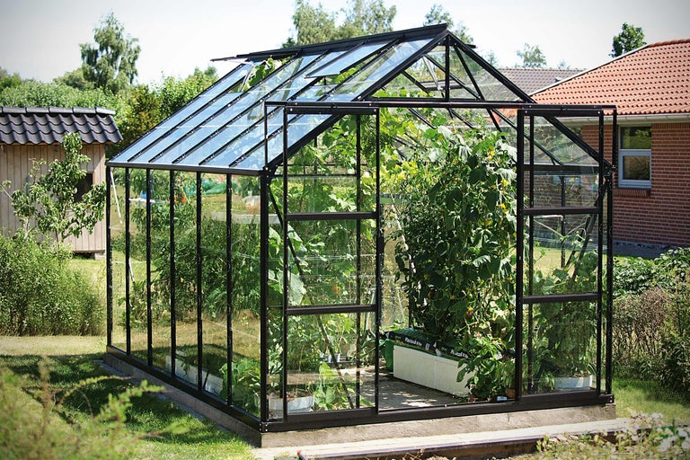 Glazen kas met planten in een tuin