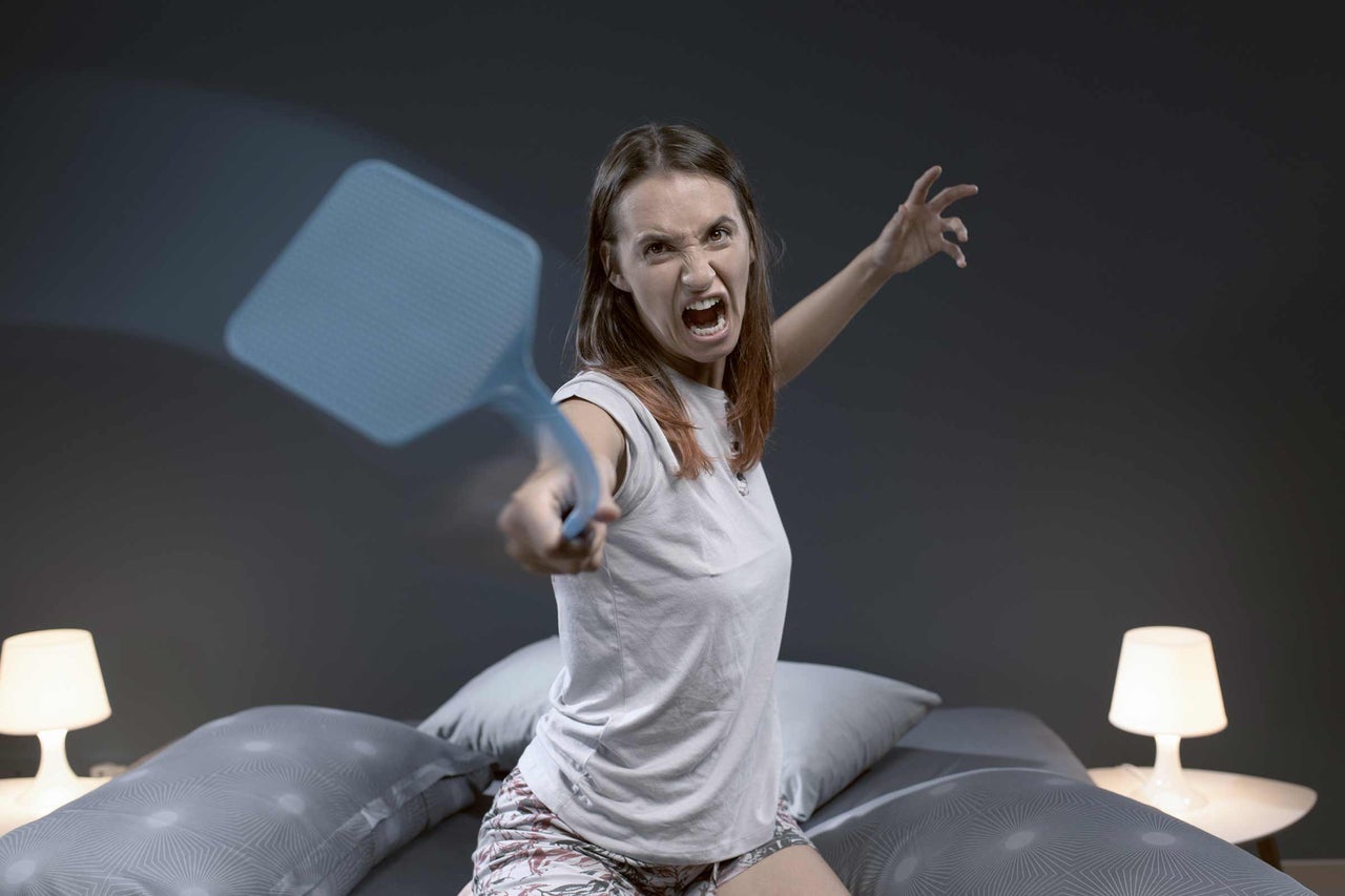 Vrouw met vliegenmepper in slaapkamer