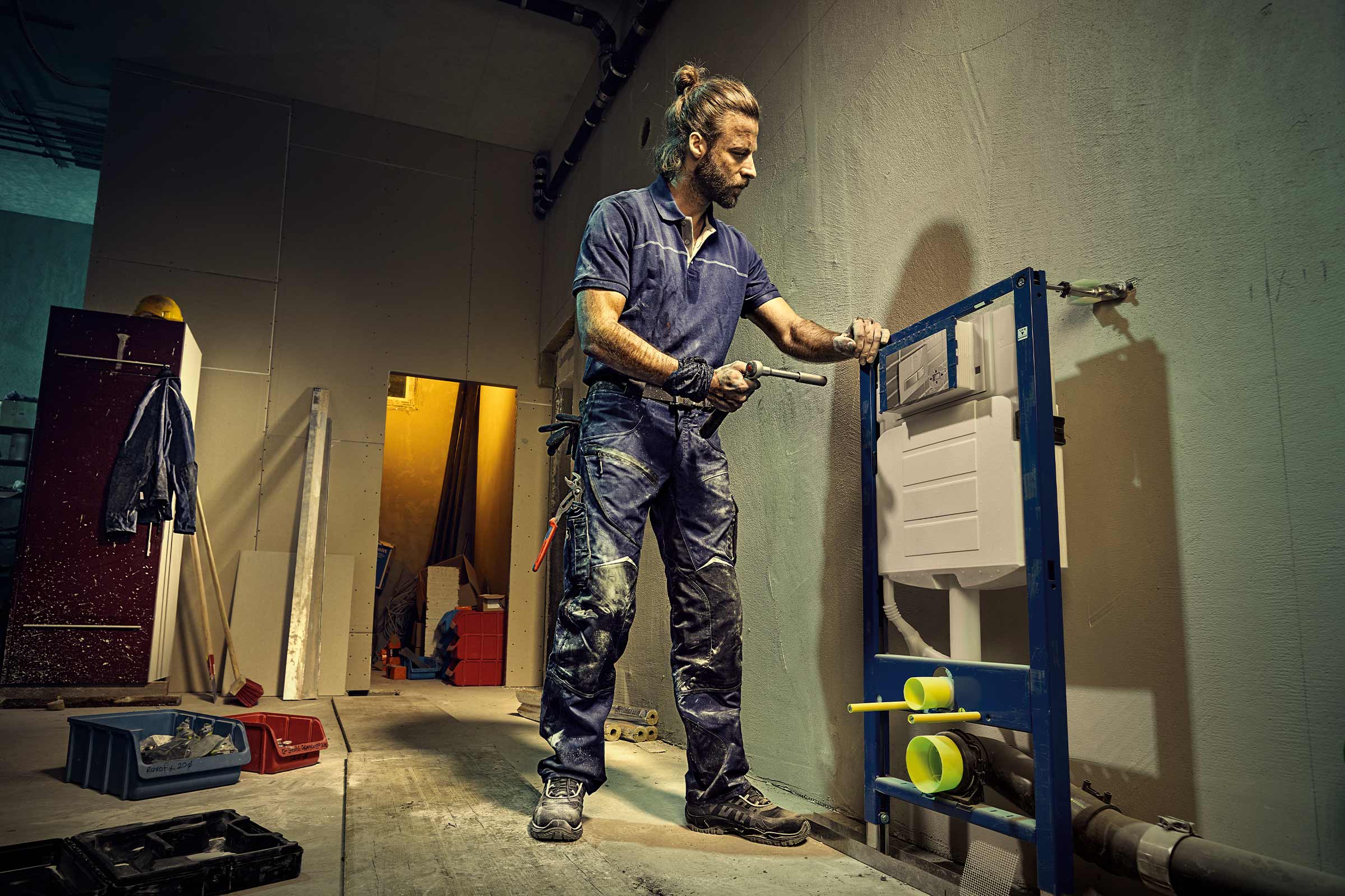 Een installateur monteert een inbouwreservoir in een ruwbouw.