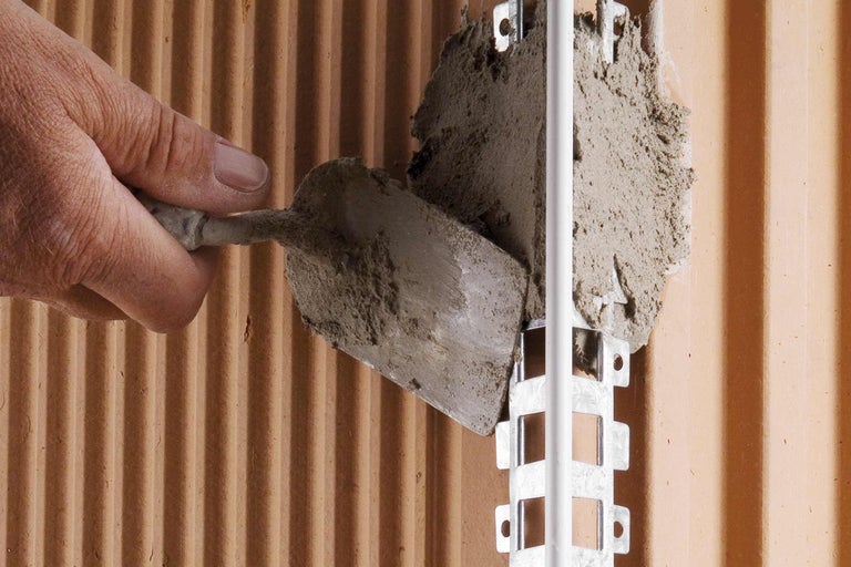 Aanbrengen van mortel op een muur met een troffel voor de installatie van een pijpklem.