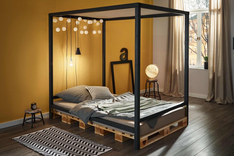 Slaapkamer met hemelbed van houten pallets en decoratie