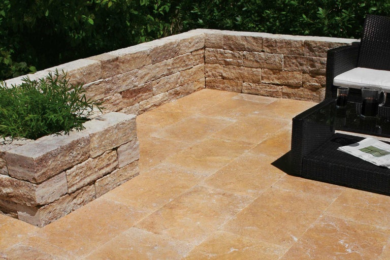 Terras met natuurstenen muur, vloerplaten en zithoek